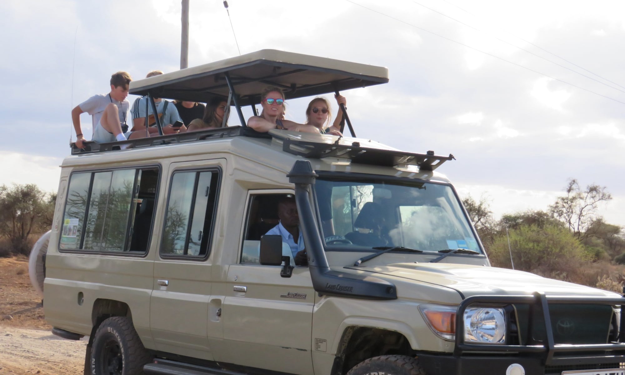Angara tours tourists viewing animals from the top of the landcruiser during game drive in Murchison falls national park, Uganda